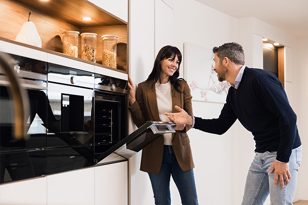 Vrouw en man bespreken de renovatie van een moderne keuken met ingebouwde oven en keukenkasten