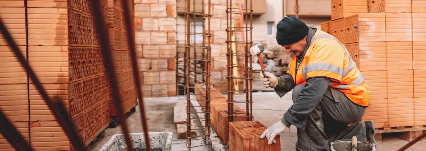 Bouwvakker met hamer plaatst bakstenen voor ruwbouwwand op een renovatieproject