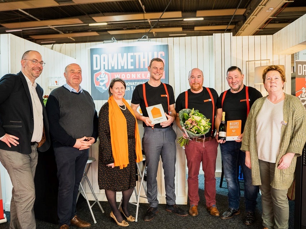 Team van De Woonwaaier en Dammehuis Woonkantoor met prijzen en bloemen bij renovatiestand