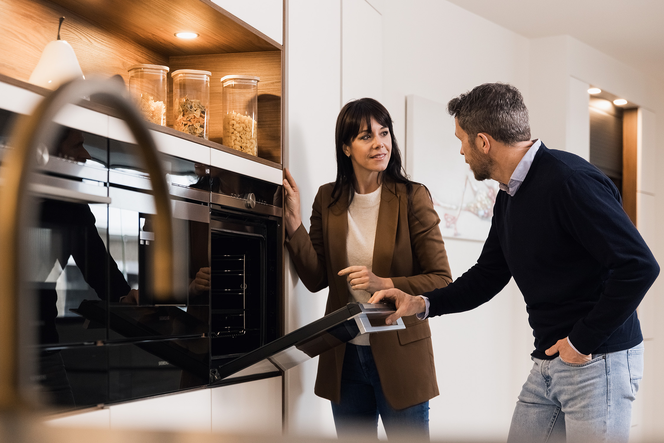 Man en vrouw bekijken samen moderne keukenoven in nieuw gerenoveerde woning