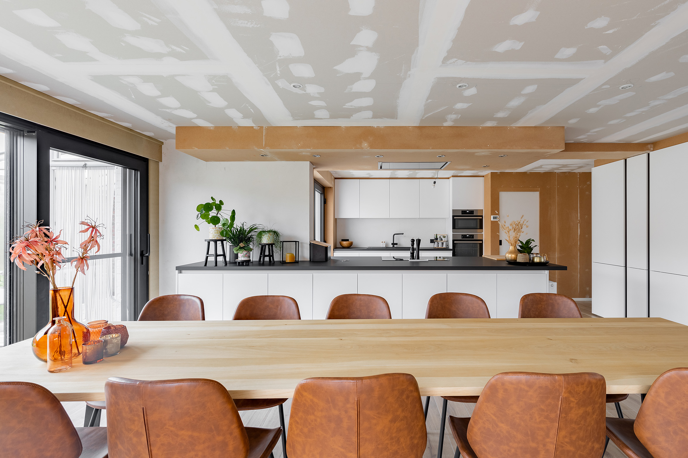 Moderne keuken en eetruimte tijdens renovatie met onafgewerkte plafonds en nieuwe meubels