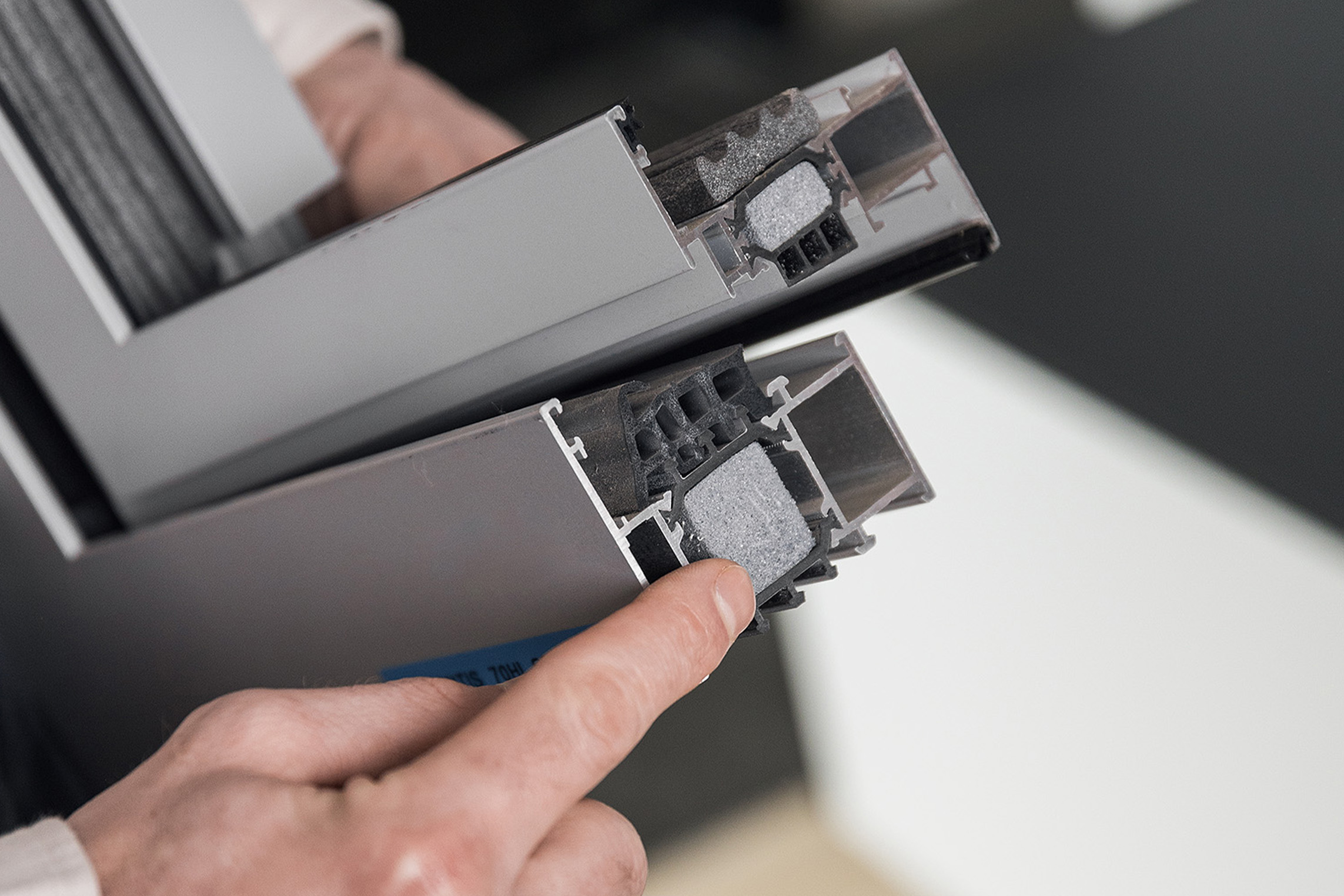 Hand wijst op aluminium raamprofielen met isolatie voor woningrenovatie door De Woonwaaier