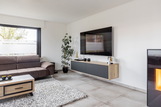 Modern ingerichte woonkamer met bruin hoekzetel, zwevend tv-meubel, grote ramen en vloerverwarming