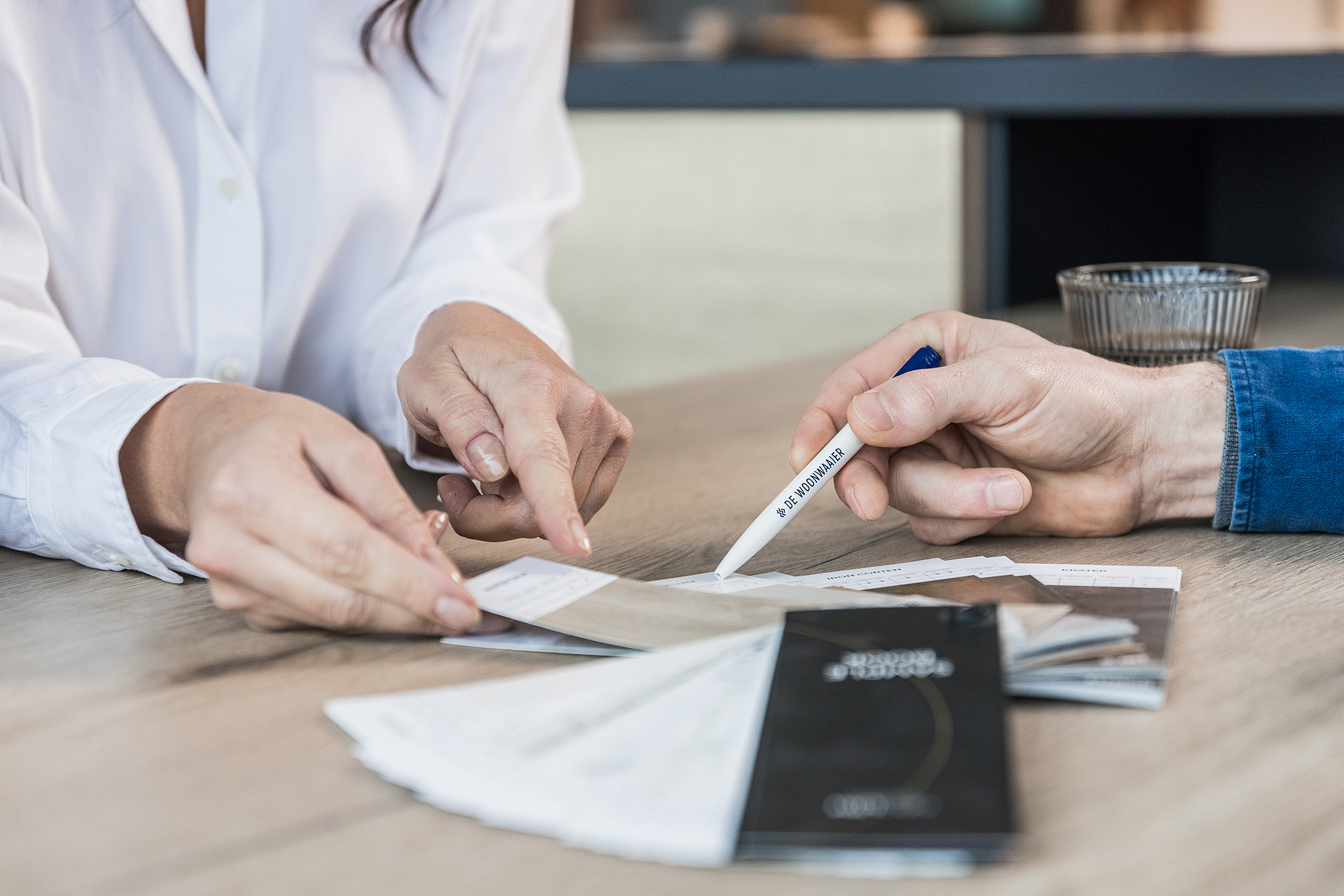 Mensen bespreken en kiezen bouwmaterialen met pen van De Woonwaaier tijdens renovatieadvies
